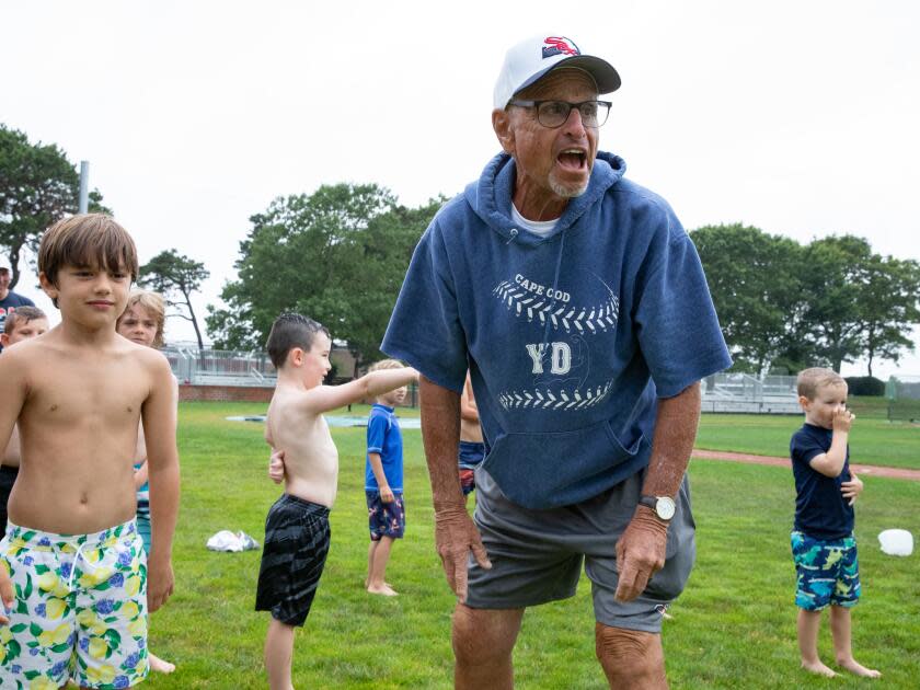 Coach Scott Pickler yells as children participating in a youth camp go through a slip and slide.