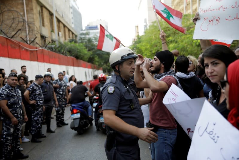 A police officer tries to move protesters back to let cars pass as they demonstrate outside of Lebanon Central Bank during ongoing anti-government protests in Beirut