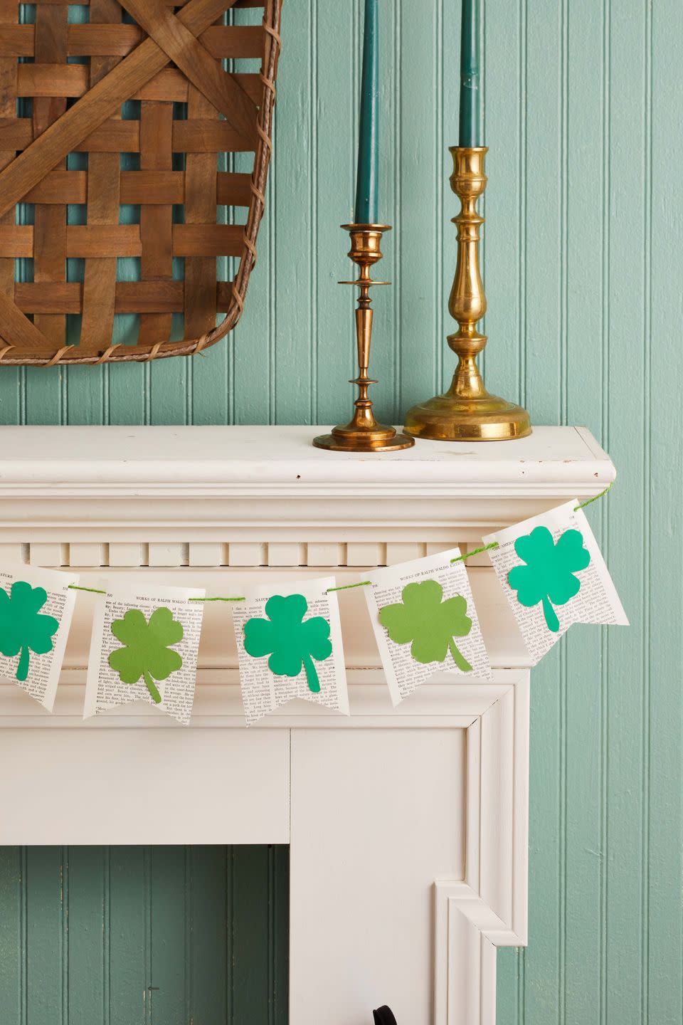 four leaf clover garland made from book pages and green paper hung on an fireplace mantel