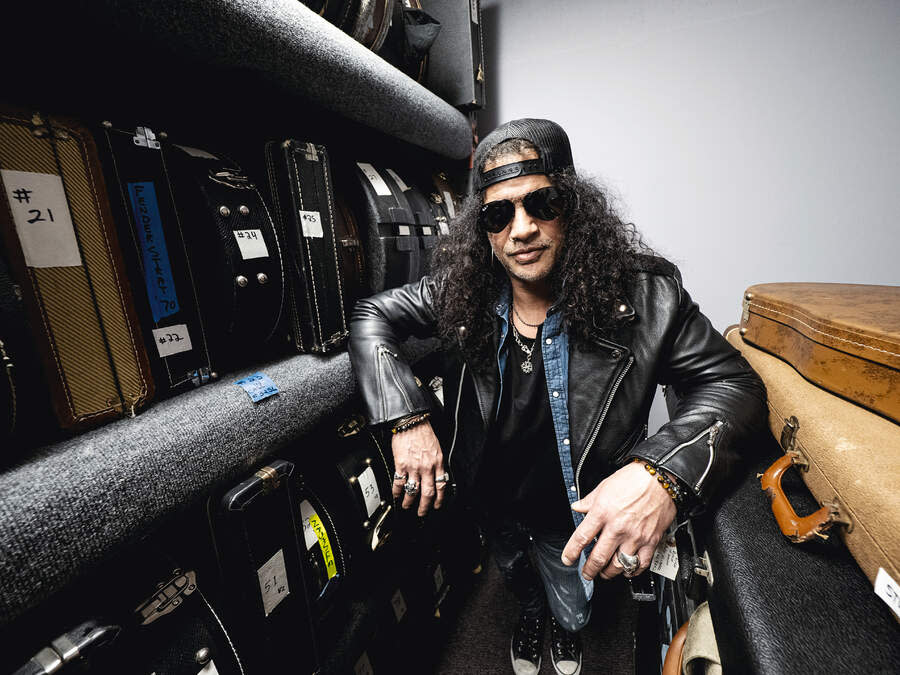 Slash backstage surrounded by guitars in flightcases