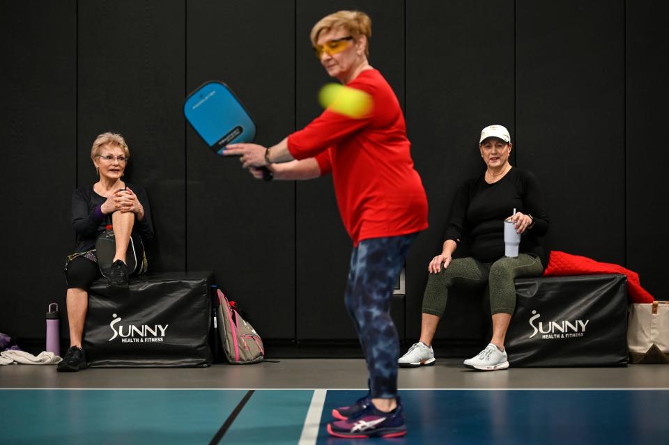 Susan Smith, left, and Sue Wilson, right, take a break from playing and watch Norma Koob, center, play pickleball on Friday, Jan. 27, 2023, at Court One Athletic Clubs in Lansing.