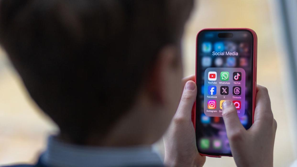 <div>A 12-year-old boy looks at an iPhone screen showing various social media apps including TikTok, Facebook and X on February 25, 2024 in Bath, England. (Photo by Matt Cardy/Getty Images)</div>