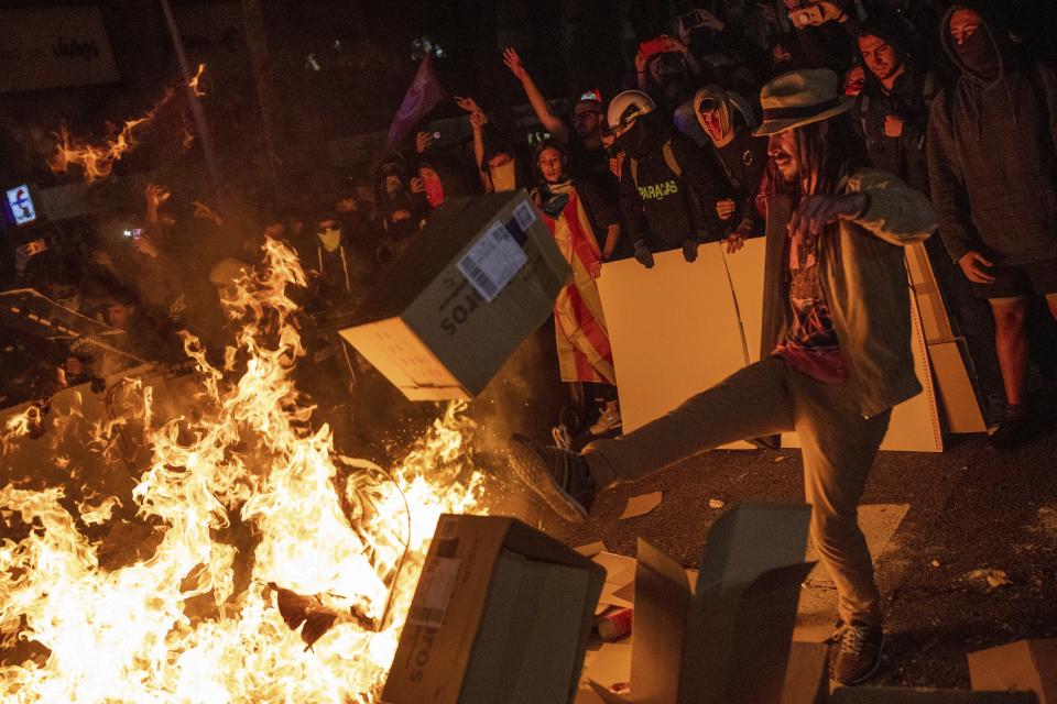 Protesters throw cartons to a burning barricade during clashes with police in Barcelona, Spain, Tuesday, Oct. 15, 2019. (Photo: Bernat Armangue/AP)