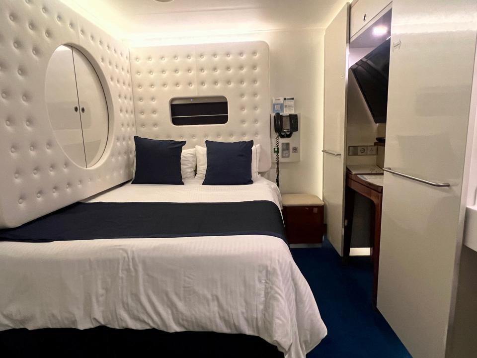 Norwegian Getaway studio stateroom interior. full bed with white cushioned paneling around it