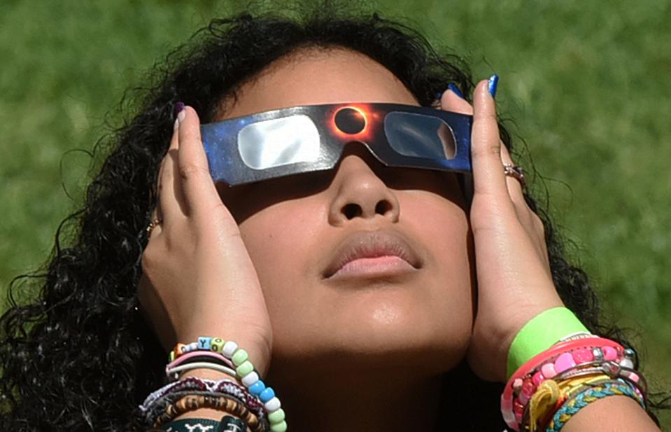 A woman watches the annular solar eclipse with safety glasses at a watch party at the Orlando Science Center on October 14, 2023 in Orlando, Florida.