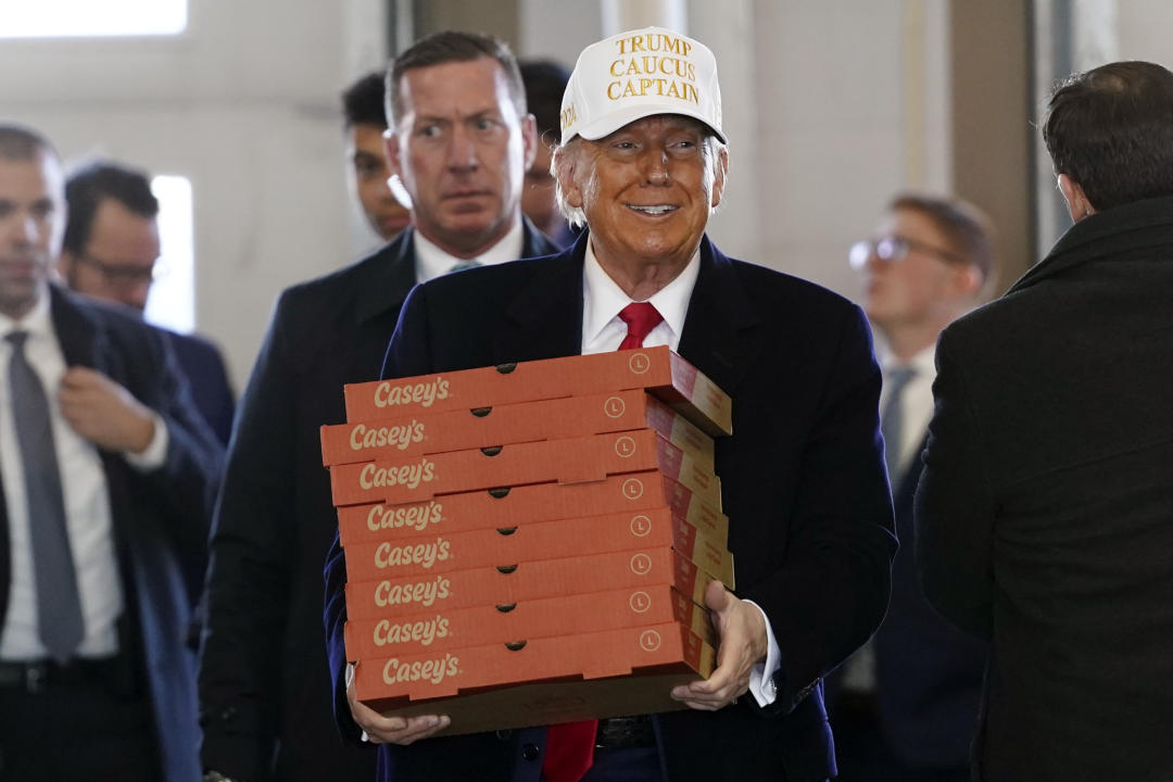 Donald Trump, in white cap saying Trump Caucus Caption, delivers pizzas to a fire department in Waukee, Iowa, on Sunday. 