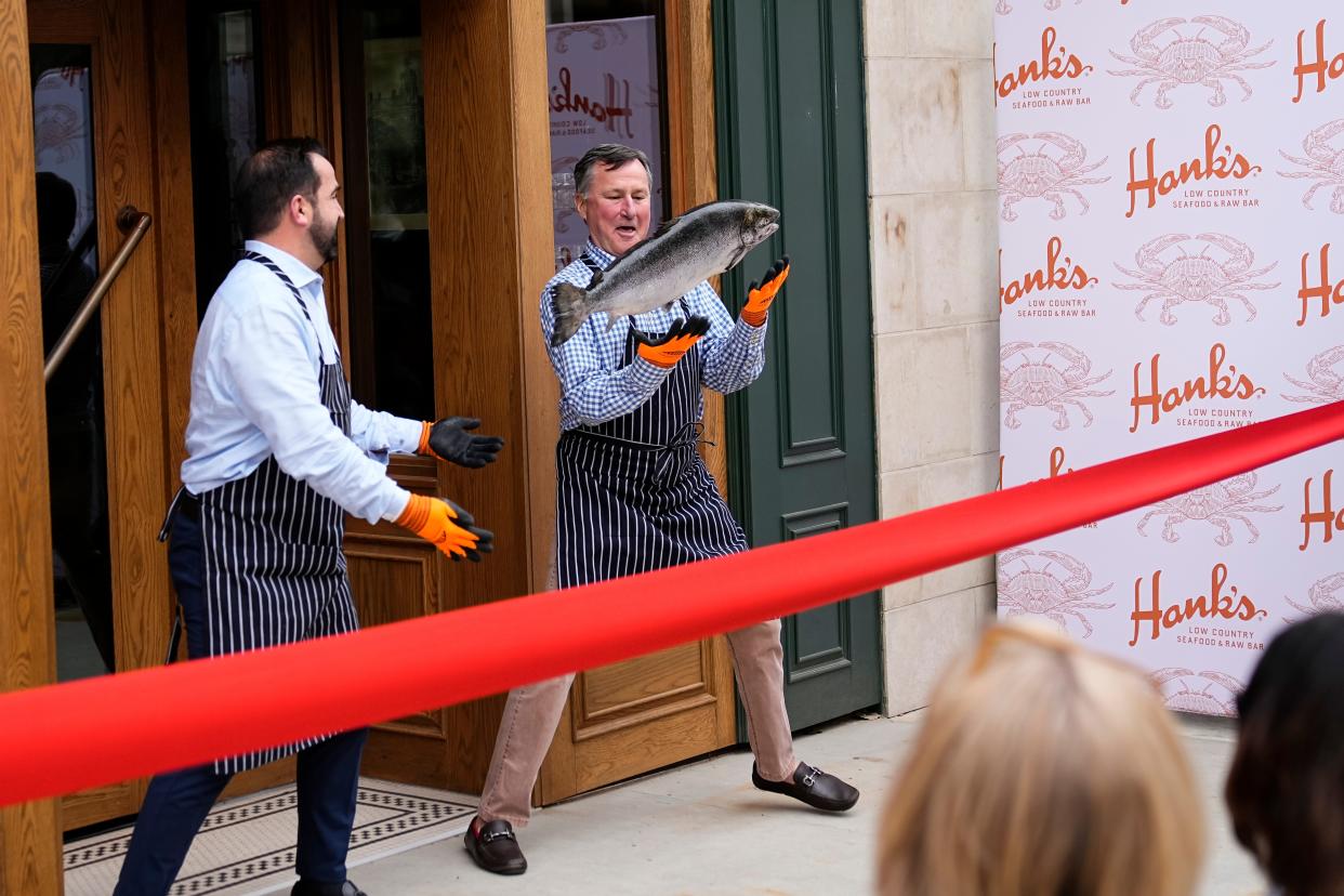 Rockbridge CEO Jim Merkel tosses a salmon to Edwards Companies CEO Jeff Edwards prior to a ribbon cutting during a the grand-opening event for Hank’s Low Country Seafood & Raw Bar at the corner of Gay and High streets. Hank’s, which opened its first restaurant in Charleston, South Carolina, includes a lounge, expansive bar, dining room, raw bar and private dining room.