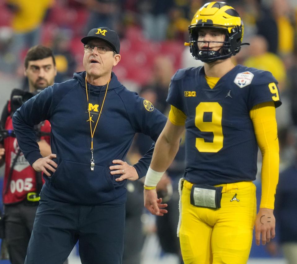 Michigan coach Jim Harbaugh watches with quarterback J.J. McCarthy (9) as his team prepares for its game against TCU in the College Football Playoff semifinal at the 2022 Fiesta Bowl at State Farm Stadium.