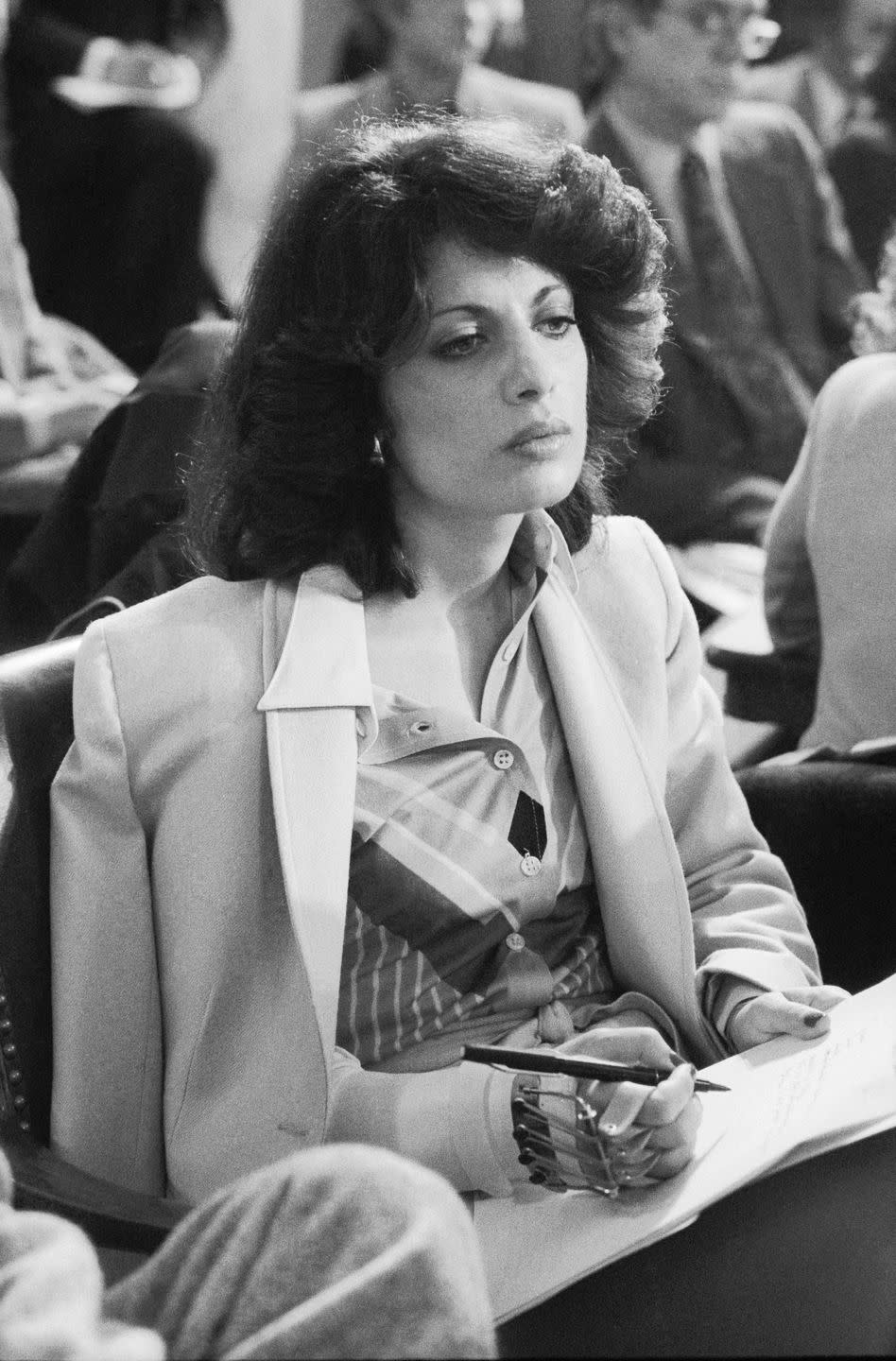 jackie speier in a button up shirt and suit jacket writing with a bandaged hand