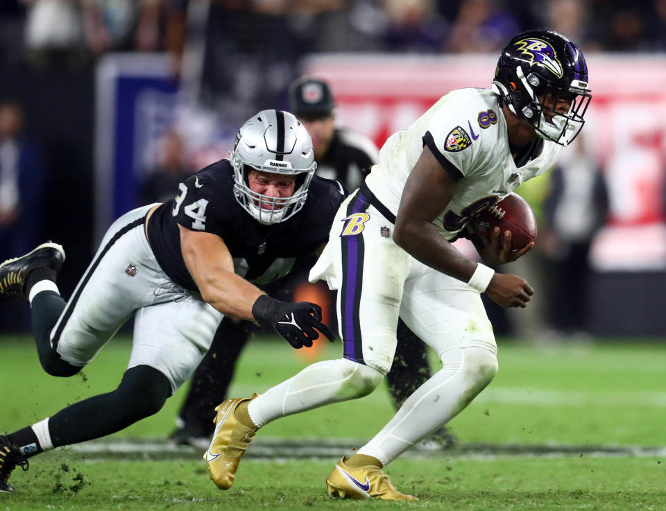 Baltimore Ravens quarterback Lamar Jackson (8) runs the ball ahead of Las Vegas Raiders defensive end Carl Nassib (94) during the second half at Allegiant Stadium.  / Credit: Mark J. Rebilas