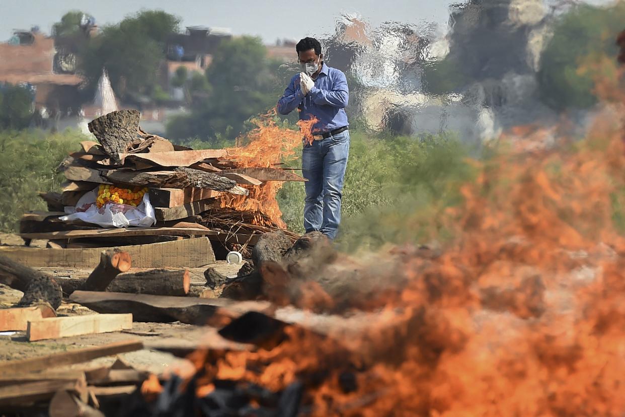 A family member offers prayers during the cremation of his loved one who died due to COVID-19 at a cremation ground in Allahabad on May 8, 2021, as India recorded more than 4,000 coronavirus deaths in a day for the first time.