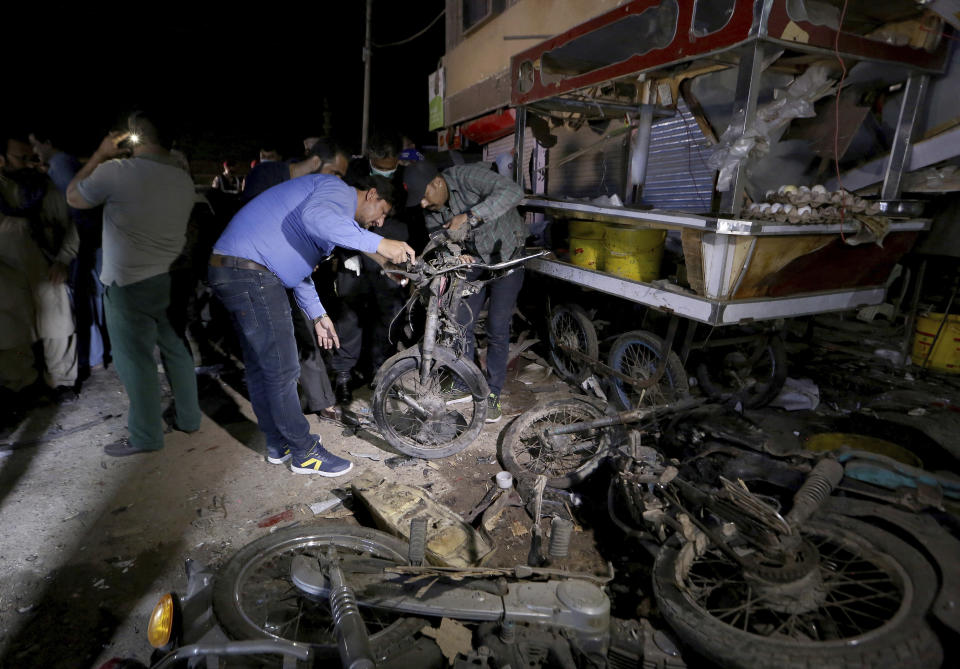 Pakistani security officials examine the site of explosion, in Karachi, Pakistan, Monday, March 15, 2021. The roadside bomb went off near a vehicle carrying paramilitary rangers in southern Pakistan on Monday, killing and wounding some people, mostly pedestrians, authorities said. (AP Photo/Fareed Khan)