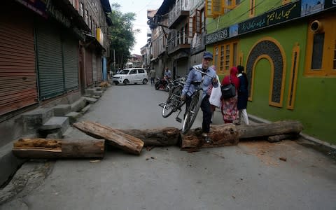 A Kashmiri man crosses a barricade set up by protesters in Srinagar, Indian controlled Kashmir, Wednesday, Aug. 28, 2019. India's government, led by the Hindu nationalist Bharatiya Janata Party, imposed a security lockdown and communications blackout in Muslim-majority Kashmir to avoid a violent reaction to the Aug. 5 decision to downgrade the region's autonomy.  - Credit: AP