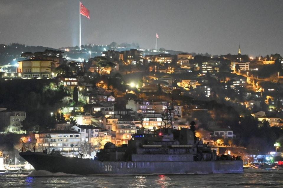 A Russian landing vessel sailing at night against the background of Istanbul buildings.