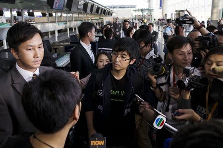 An airline's staff (L) speaks to Hong Kong Federation of Students leader Alex Chow (C) after he was refused to board the plane at the Hong Kong International Airport November 15, 2014. REUTERS/Tyrone Siu