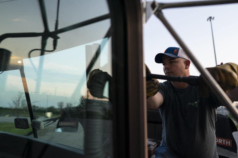 In this April 5, 2020, photo, Sammy Lloyd, of Ringgold, Ga., washes the windshield of his semitruck during a fuel stop at the Fas Mart in Winchester, Ky. Lloyd is pulling a COVID-19 emergency relief load from California to Virginia. (AP Photo/Carolyn Kaster)