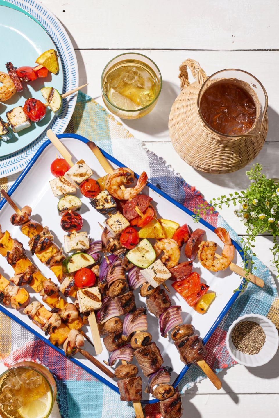 four different kinds of grilled kebabs on a white rectangle serving tray with blue trim