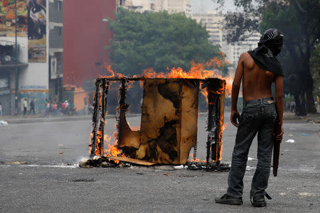 A demonstrator stands next to a burning barricade during a protest against the government of Venezuelan President Nicolas Maduro in Caracas, Venezuela March 31, 2019. REUTERS/Carlos Garcia Rawlins