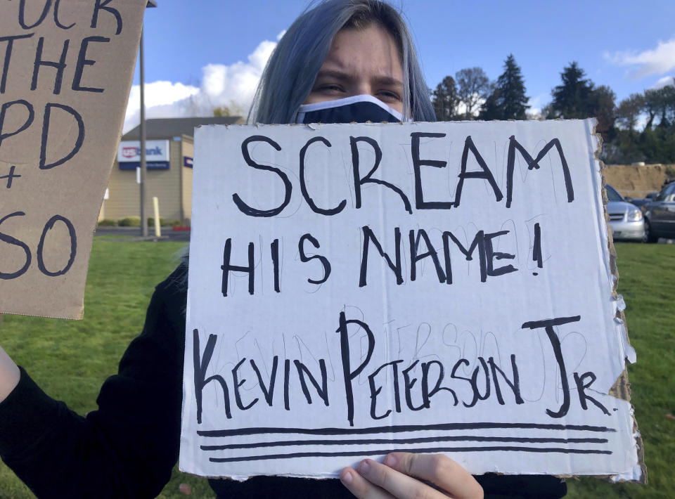 A Black Lives Matter protester holds a sign in Hazel Dell, Wash. on Friday, Oct. 30, 2020, honoring a 21-year-old Black man Kevin Peterson Jr, who was fatally shot by law-enforcement in Clark County Washington the day before. (AP Photo/Gillian Flaccus)