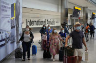 Passengers arrive at Terminal 5 of Heathrow Airport in London, Monday, Aug. 2, 2021. Travelers fully vaccinated against coronavirus from the United States and much of Europe were able to enter Britain without quarantining starting today, a move welcomed by Britain's ailing travel industry. (AP Photo/Matt Dunham)