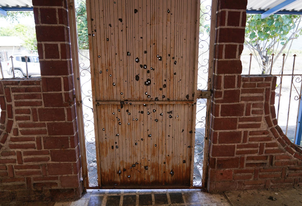 A door riddled with bullet holes in an abandoned home in El Limoncito in Michoacan state, Mexico, Saturday, Oct. 30, 2021. The Mexican army has largely stopped fighting drug cartels here, instead ordering soldiers to guard the dividing lines between gang territories so they won’t invade each other’s turf — and turn a blind eye to the cartels’ illegal activities just a few hundred yards away. (AP Photo/Eduardo Verdugo)