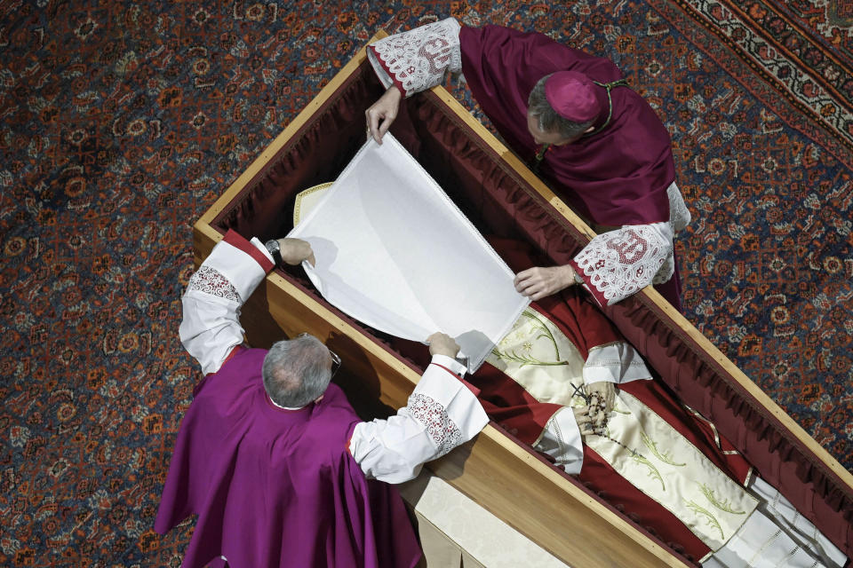 In this image released on Thursday, Jan. 5, 2023, by the Vatican Media news service, Bishops Georg Gaenswein, right, and Diego Ravelli cover the face of Pope Emeritus Benedict XVI with a white silk veil as he rests in a cypress coffin in St. Peter's Basilica, Wednesday, Jan. 4, 2023, the night before his funeral mass presided over by Pope Francis at the Vatican. Benedict died at 95 on Dec. 31 in the monastery on the Vatican grounds where he had spent nearly all of his decade in retirement. He was 95. (Vatican Media via AP)