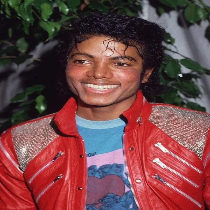 Michael sonriendo mientras viste su famosa chaqueta de cuero roja