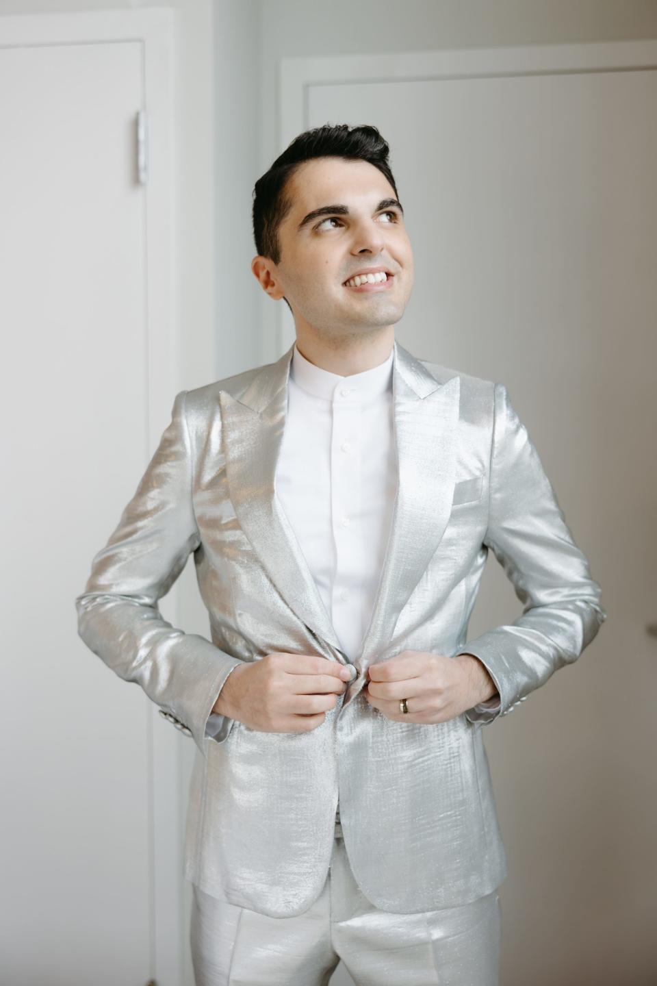 A man in a silver jacket and pants stands in a room.