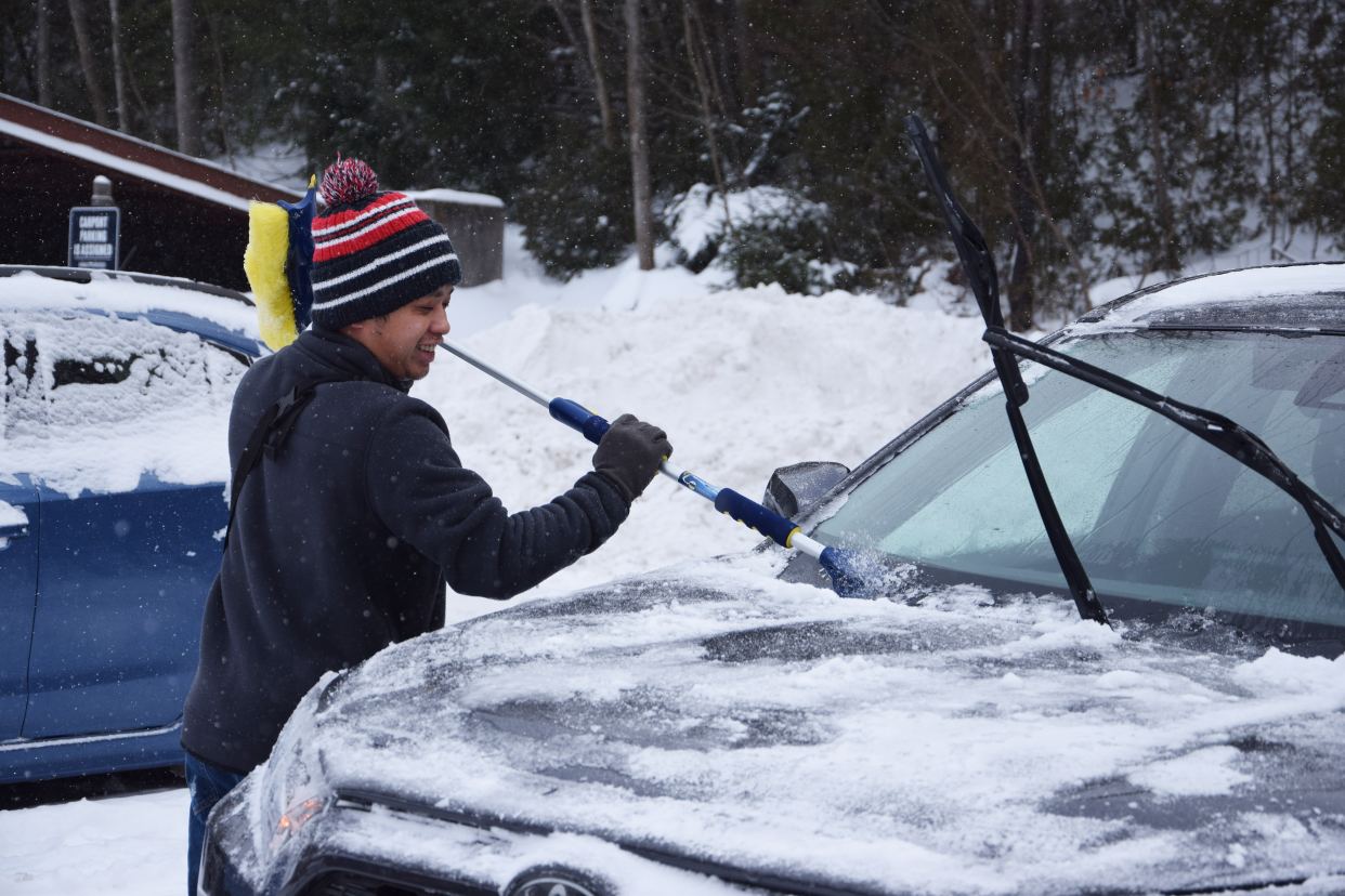 Jeffrey Yang scrapes ice and snow off his car in Petoskey following a winter storm Saturday, Jan. 13, 2024.