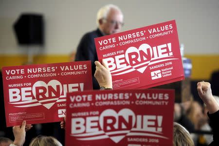 Supporters from the Nurses for Bernie Super PAC wave signs as U.S. Democratic presidential candidate Bernie Sanders speaks at a campaign event at United Steelworkers Local 310L in Des Moines, Iowa January 26, 2016. REUTERS/Mark Kauzlarich