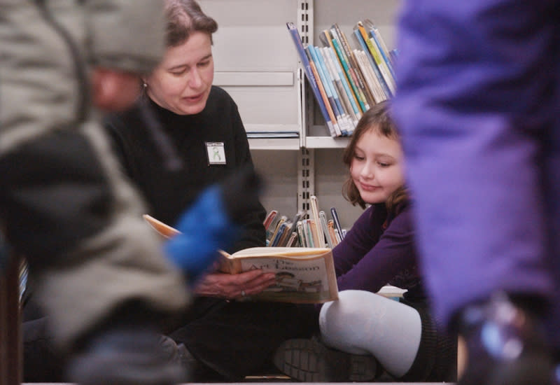 A mother reads to her daughter at the Toronto Public Library’s High Park location in 2010. The Dial-a-Story program makes it possible for children to be read stories on the phone at no cost. Photo from Getty Images.