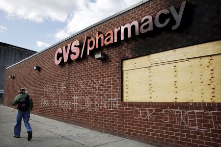 A man walks by a pharmacy damaged from riots after the death of Freddie Gray in Baltimore, Maryland, May 13, 2015. REUTERS/Carlos Barria