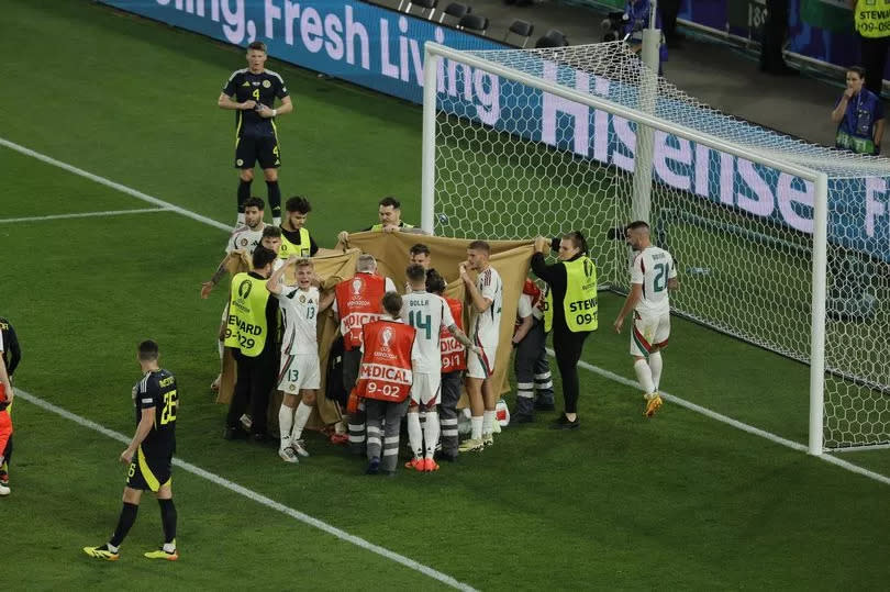 Photo shows Hungary players holding a blanket to cover teammate Barnabas Varga during Sunday's game