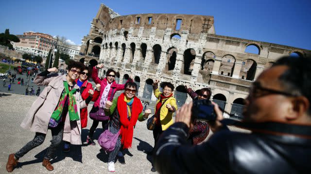 Tourists pose in front of the Colosseum in Rome.