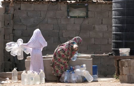 A Libyan woman displaced from the town of Tawergha fills containers with water at a displaced camp in Benghazi