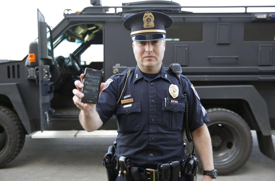 <p> In a May 6, 2014 photo, Sgt. Andres Wells of the Kalamazoo Dept. of Public Safety, who successfully used text messaging to negotiate with a suicidal robbery suspect during a 2011 standoff, stands next to his armored vehicle. With 6 billion text messages exchanged daily in the United States, texting is becoming a more frequent part of police crisis negotiations. (AP Photo/Mark Bugnaski) </p>