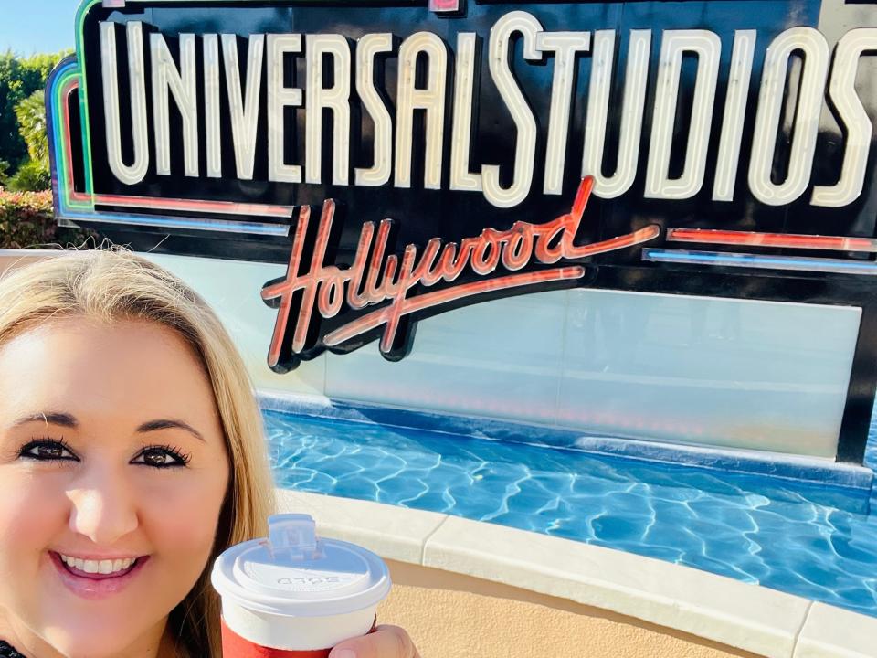 carly posing for a selfie in front of the universal studios hollywood sign at the theme park