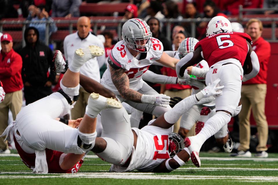 Ohio State defensive tackle Michael Hall Jr. (51) and defensive end Jack Sawyer (33) bring down Rutgers running back Kyle Monangai.