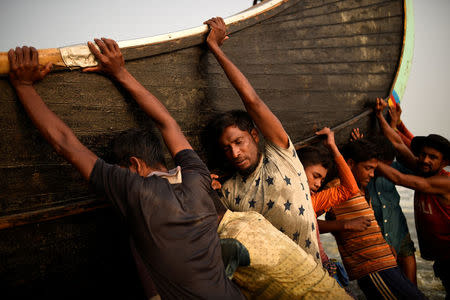 Rohingya refugees push a fishing boat from the sea at Shamlapur beach in Cox's Bazar, Bangladesh, March 24, 2018. REUTERS/Clodagh Kilcoyne