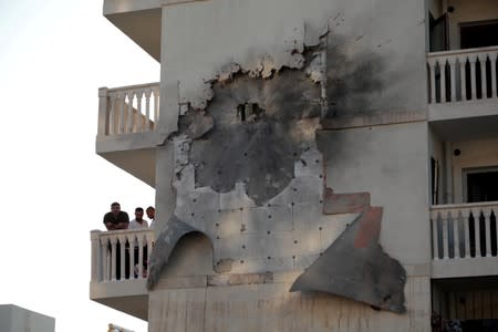 People look out from an apartment building which was damaged by a rocket fired from Syria, in Nusaybin