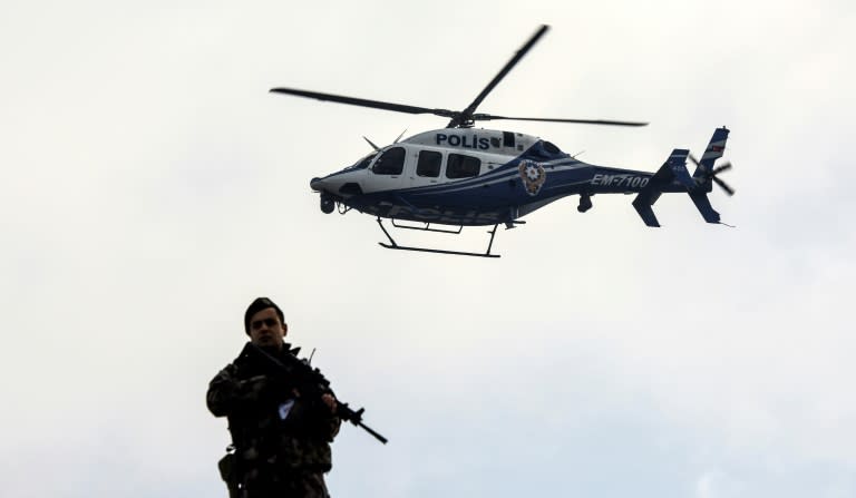 A police helicopter flies over a member of security forces near a courthouse in Mugla, western Turkey, on February 20, 2017