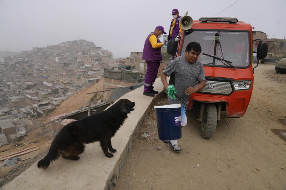 Un vecino recoge un cubo y aserrín, como parte del programa de saneamiento alternativo, en el barrio de Pamplona Alta de Lima, Perú, el miércoles 20 de marzo de 2024. El servicio incluye el reparto de aserrín, la instalación del baño seco y el traslado de los desechos hacia un contenedor que semanalmente lleva 40 toneladas a un relleno sanitario. (AP Foto/Martín Mejía)