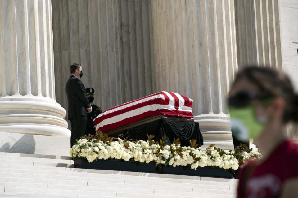 Mourners walk by Ginsburg’s flag-draped casket.