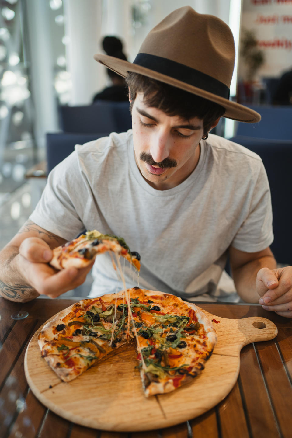 person eating pizza off of a wooden cutting board