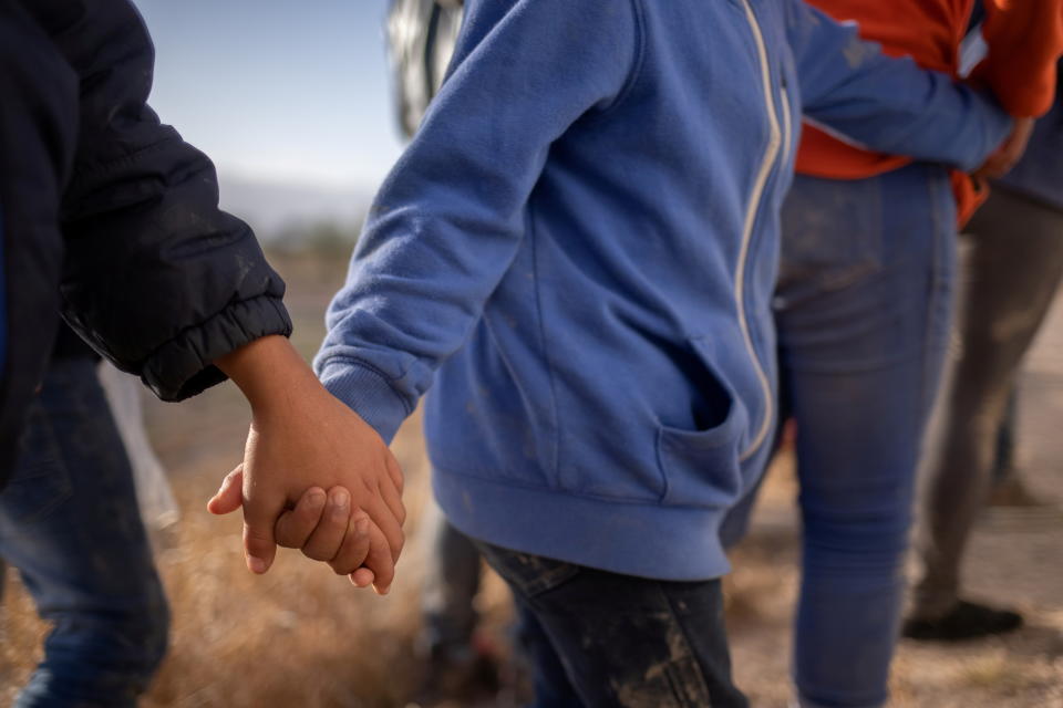 Asylum seeking unaccompanied minors hold hands as they await transport after crossing the Rio Grande river into the United States from Mexico on a raft in Penitas, Texas, on March 12, 2021. The unrelated minors are all from Honduras.   (Adrees Latif/Reuters)