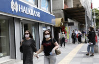 People wearing face masks for protection against the coronavirus, walk in Ankara, Turkey, Monday, May 11, 2020. Shopping malls, barber shops, hairdressers and beauty salons have reopened for business across Turkey for the first time in seven weeks as the country gradually eases restrictions aimed to prevent the spread of the new coronavirus.(AP Photo/Burhan Ozbilici)