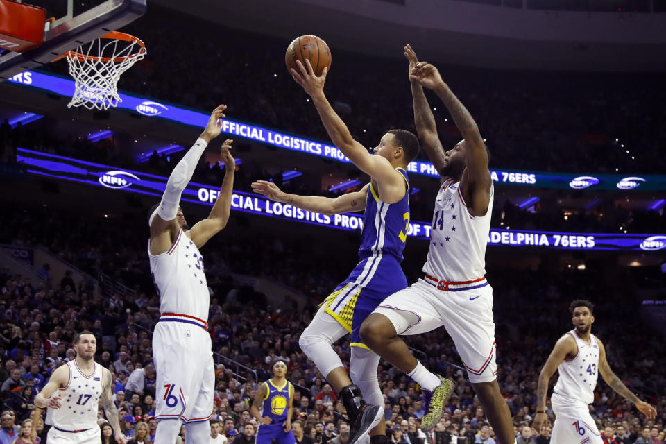 Golden State Warriors' Stephen Curry, center, goes up for a shot between Philadelphia 76ers' Tobias Harris, left, and Jonathon Simmons during the first half of an NBA basketball game, Saturday, March 2, 2019, in Philadelphia. (AP Photo/Matt Slocum)