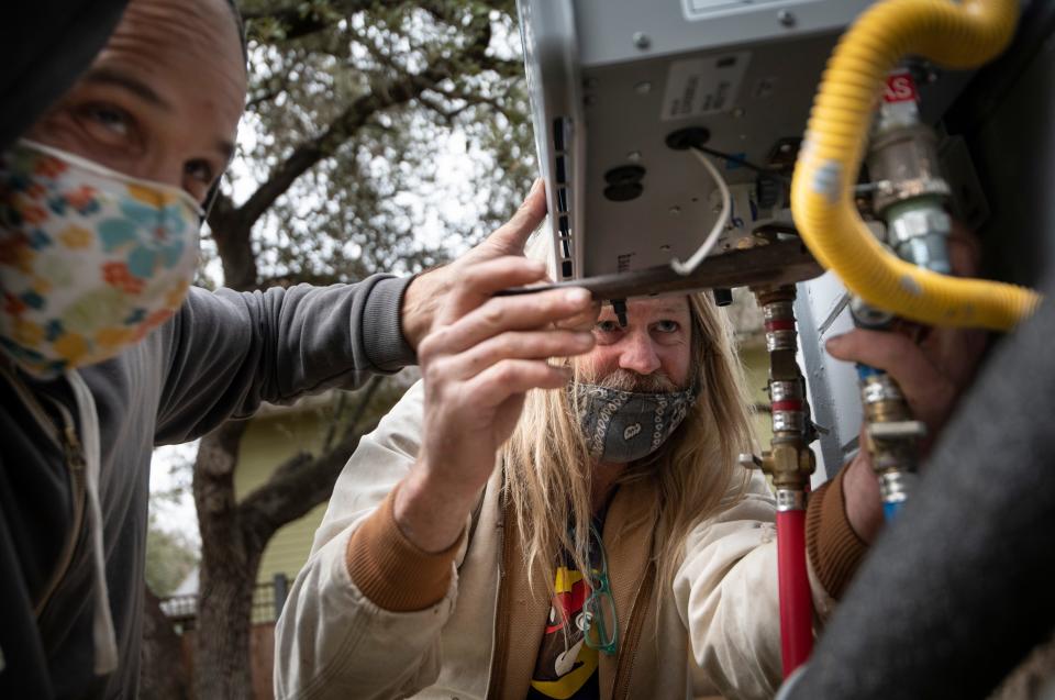 Michael Kunitzky and Coleman Kelly of the Austin Guerrilla Plumber Corps work to replace a water heater Thursday, Feb. 25, 2021 in Austin, Texas. The corps of five friends, is working to repair underprivileged residents&#x002019; plumbing problems caused by the winter storm. 