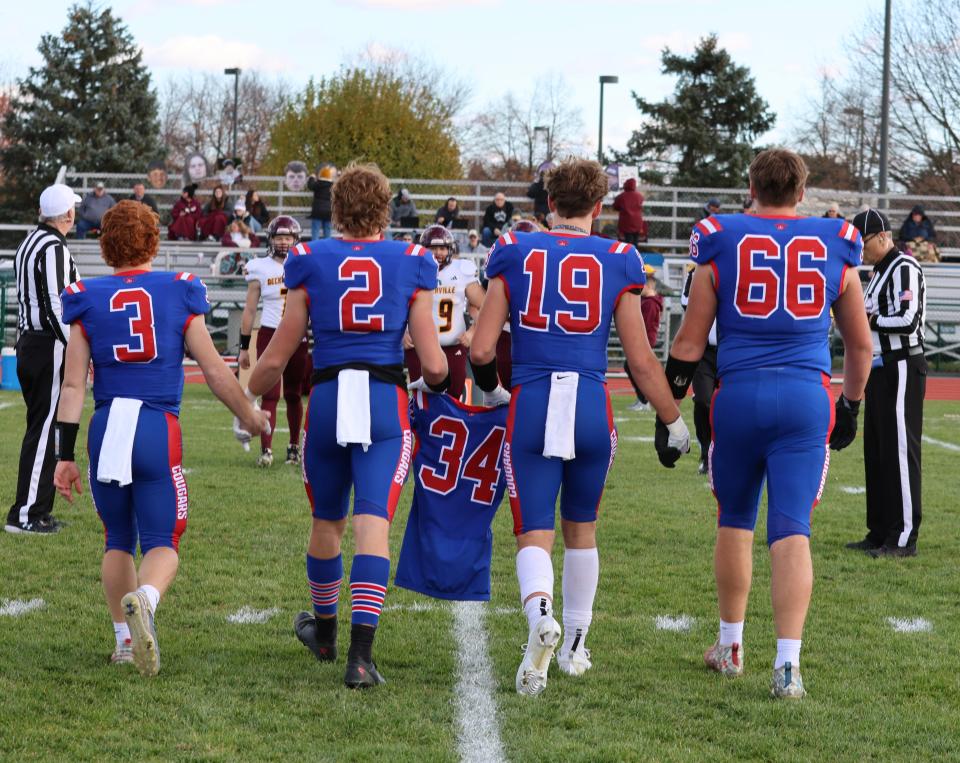 Lenawee Christian captains Sam Lutz (3), Jesse Miller (2), Paul Towler (19) and Tyler Salenbien (66) walk out for the coin toss with Nathan Bowen's No. 34 jersey prior to Saturday's Division 2 8-Player semifinal against Deckerville.