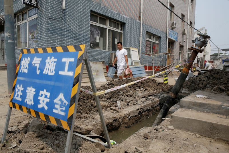 FILE PHOTO: A villager walks past the gas pipeline construction instead of coal-powered boilers in Xiaozhangwan village of Tongzhou district on the outskirts of Beijing